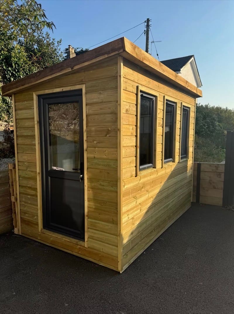 A timber garden room with glazed doors at the end of a garden