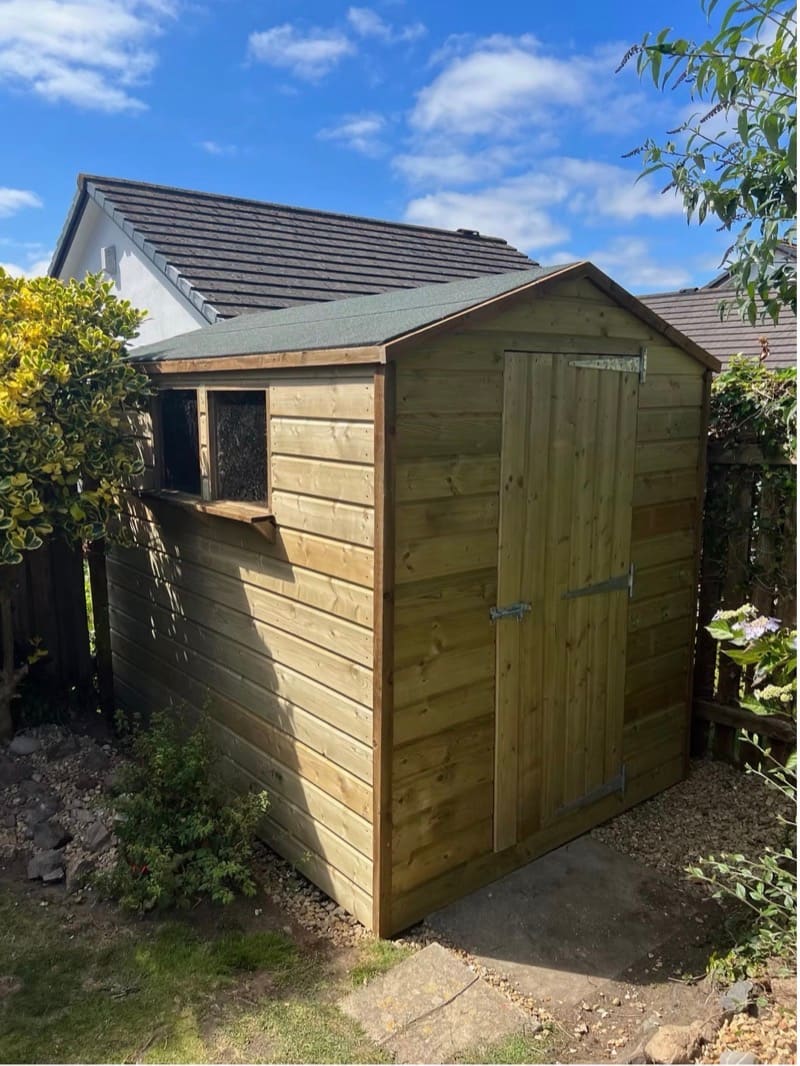 A custom timber shed with an apex roof, built and installed in a Cornish garden