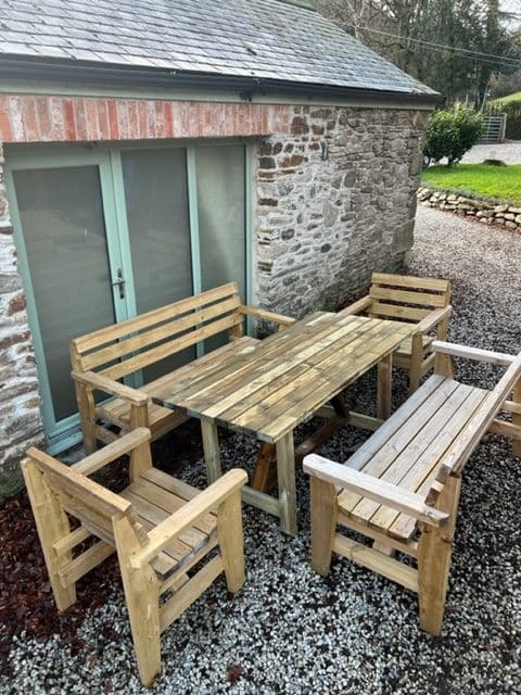 The Full Comfort 8 Seater dining set, a table with two benches and two chairs, in a garden