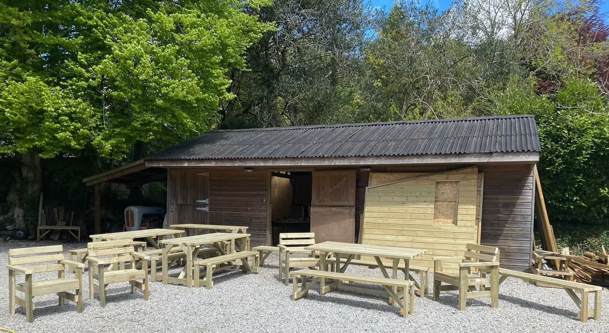 Handmade timber benches lined up in front of the Turps Wood Design workshop in Lostwithiel